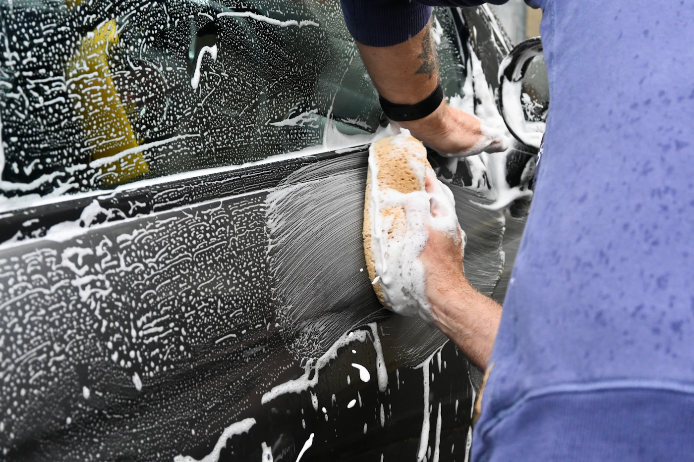 Car bodywork being washed with automotive cleaning supplies